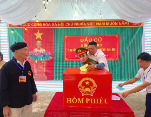 Hình ảnh lực lượng Công an xã hỗ trợ cử tri cao tuổi bị cụt hai chân tham gia bỏ phiếu tại điểm bầu cử