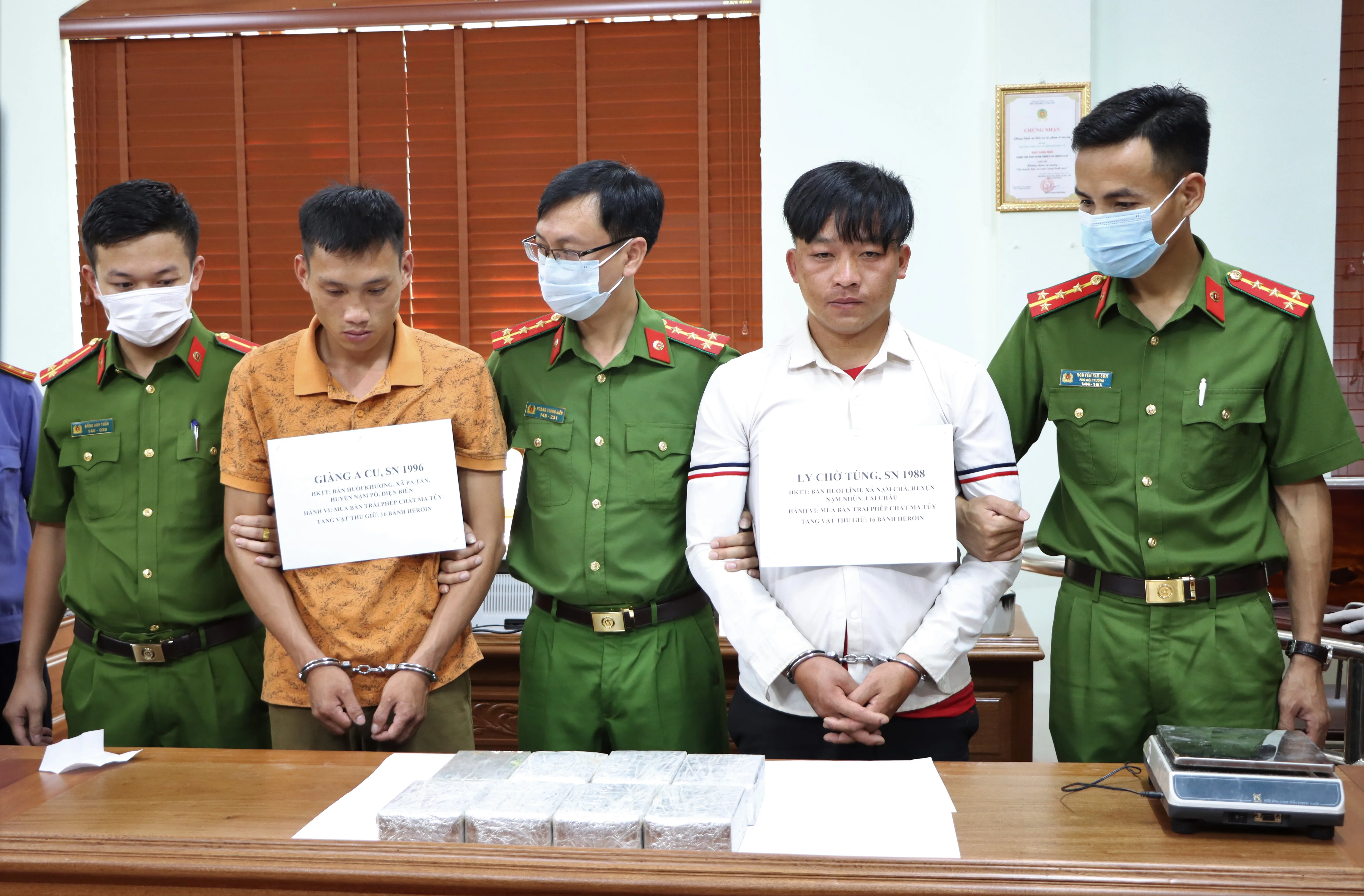 Hai đối tượng Tùng (áo trắng) và Cu (áo vàng) cùng 16 bánh heroin tại cơ quan điều tra