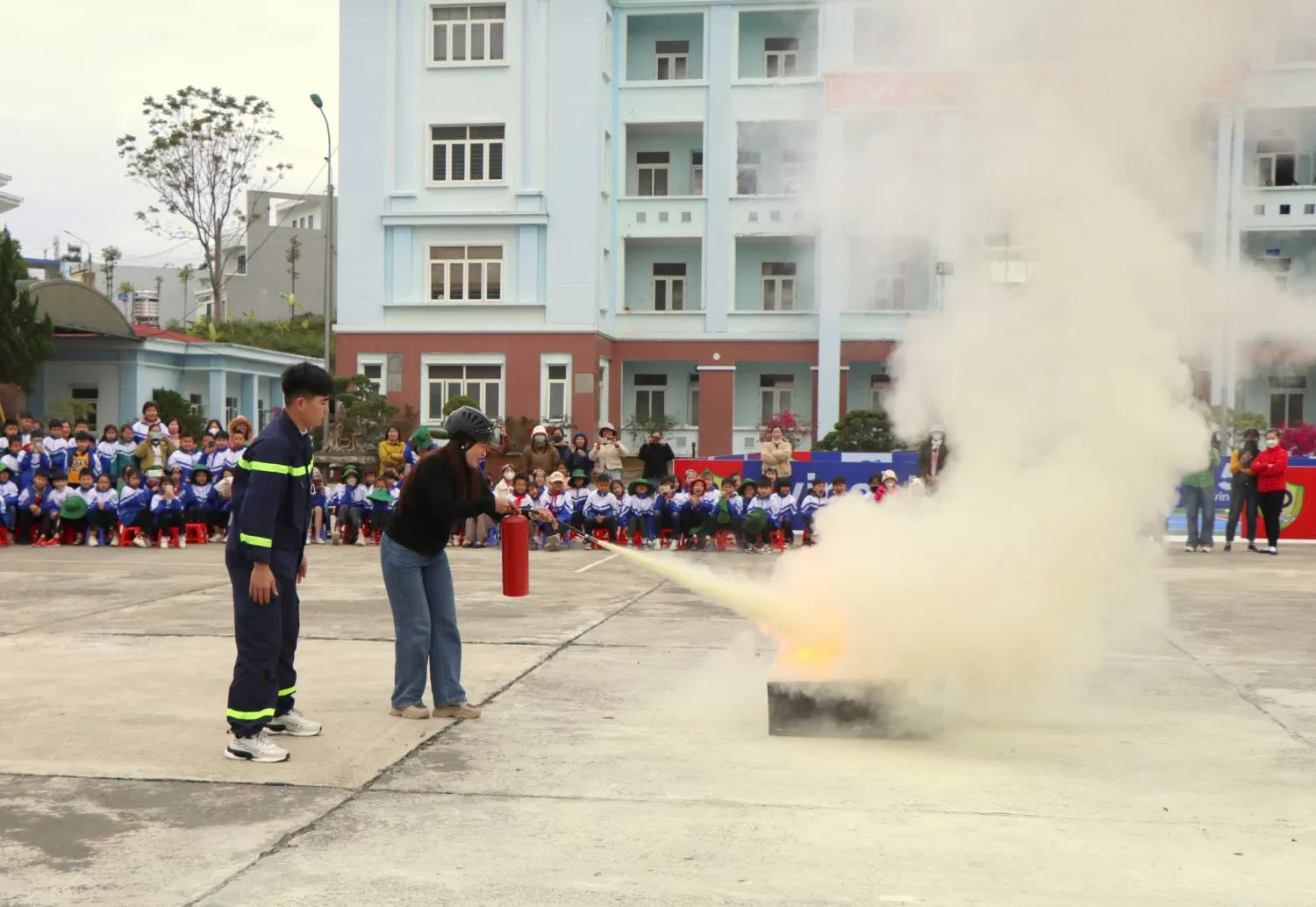 Giáo viên Trường Tiểu học Quyết Thắng thực hành dập đám cháy xăng dầu bằng bình chữa cháy.