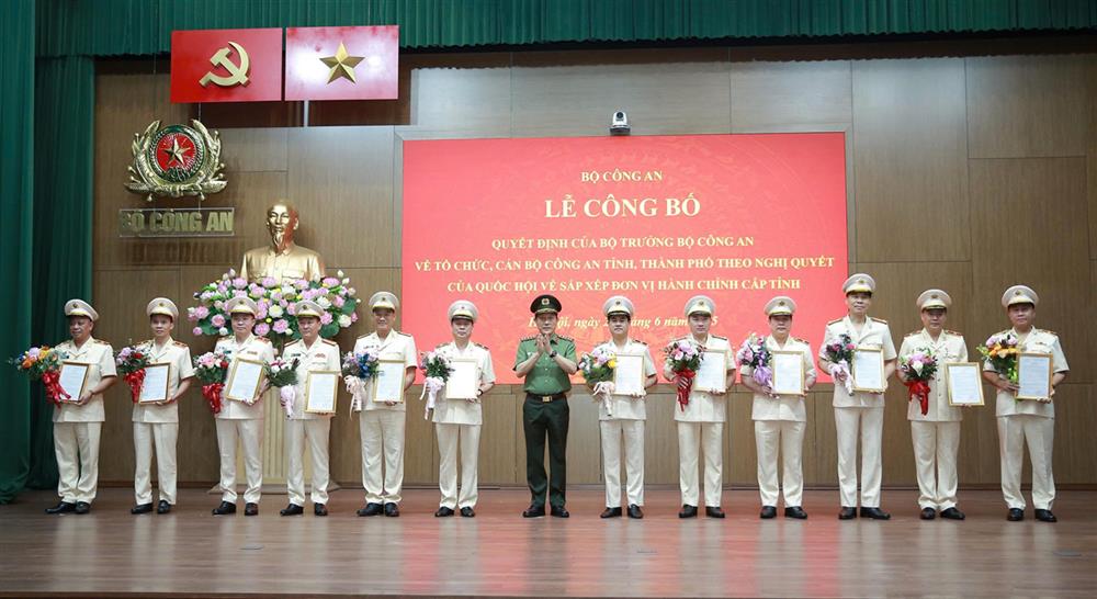 Bộ trưởng Lương Tam Quang trao Quyết định và tặng hoa chúc mừng 23 đồng chí Giám đốc Công an địa phương sau sáp nhập.
