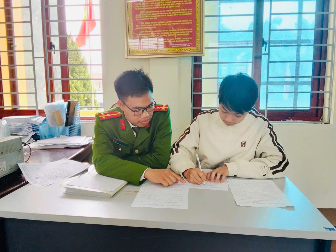 Cán bộ Công an xã hỗ trợ, hướng dẫn công dân hoàn thiện thủ tục đăng ký dự tuyển.