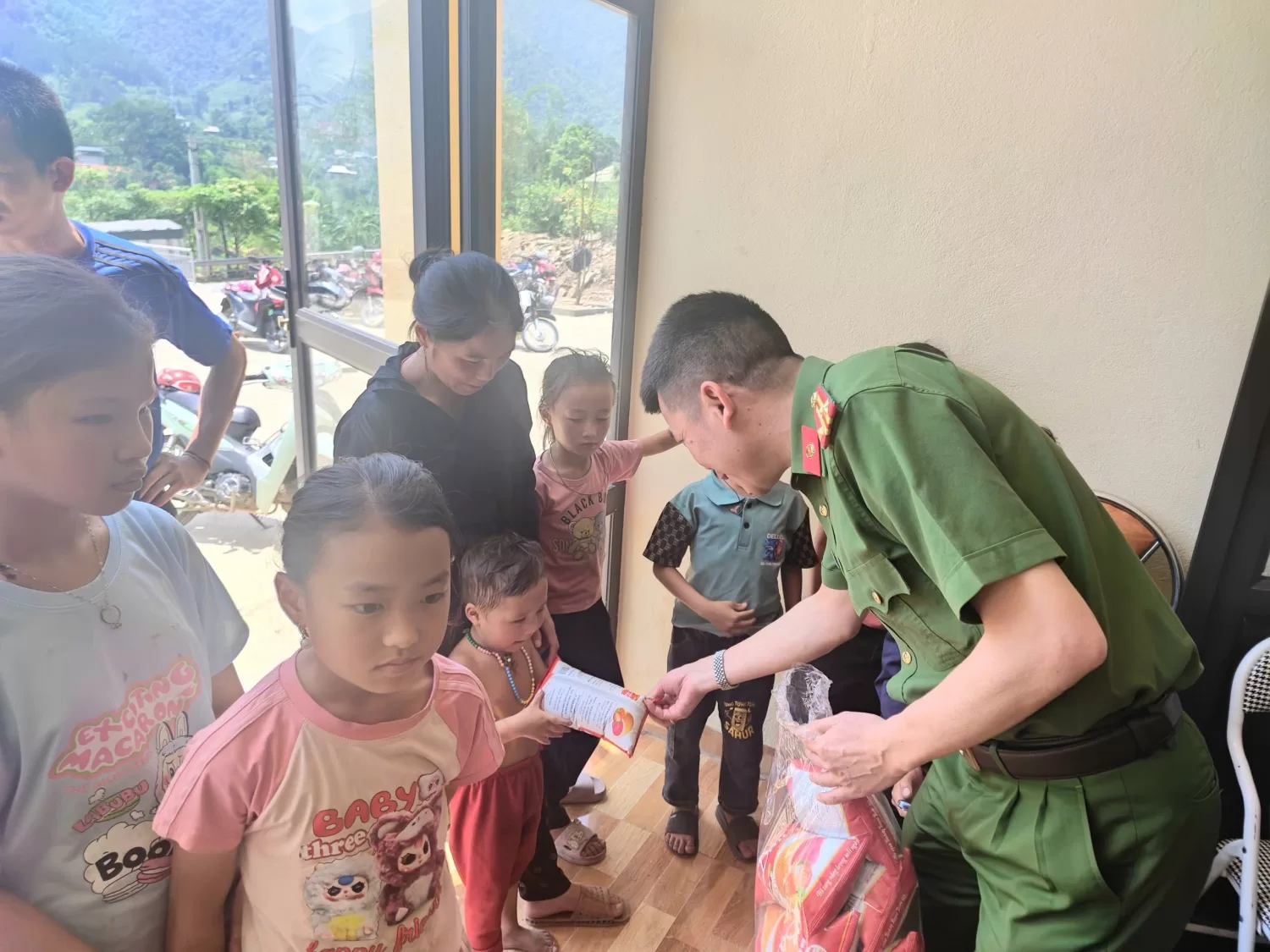 Lãnh đạo Công an xã Mường Kim tận tay trao bánh mỳ, nước uống cho các cháu nhỏ và người dân trong thời gian chờ làm thủ tục định danh điện tử.