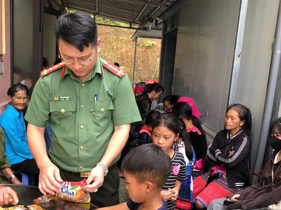 Cán bộ Công an xã phát bánh kẹo cho các cháu nhỏ và người dân khi đến làm thủ tục hành chính tại trụ sở Công an xã